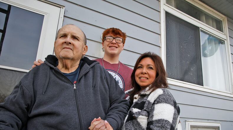 Burnadette Underwood with her son, Derek, and father, Louis Gonzales, in front of their Park Layne house Thursday, Dec. 21, 2023. Burnadette is the winner of Van Martin Roofing's "Win a New Roof on the House" program, which gives a new roof to a lucky home owner in the Miami Valley twice a year. Burnadette, who is currently taking care of her elderly father, who has cancer, was nominated by her daughter and was selected from over 50 applicants. BILL LACKEY/STAFF