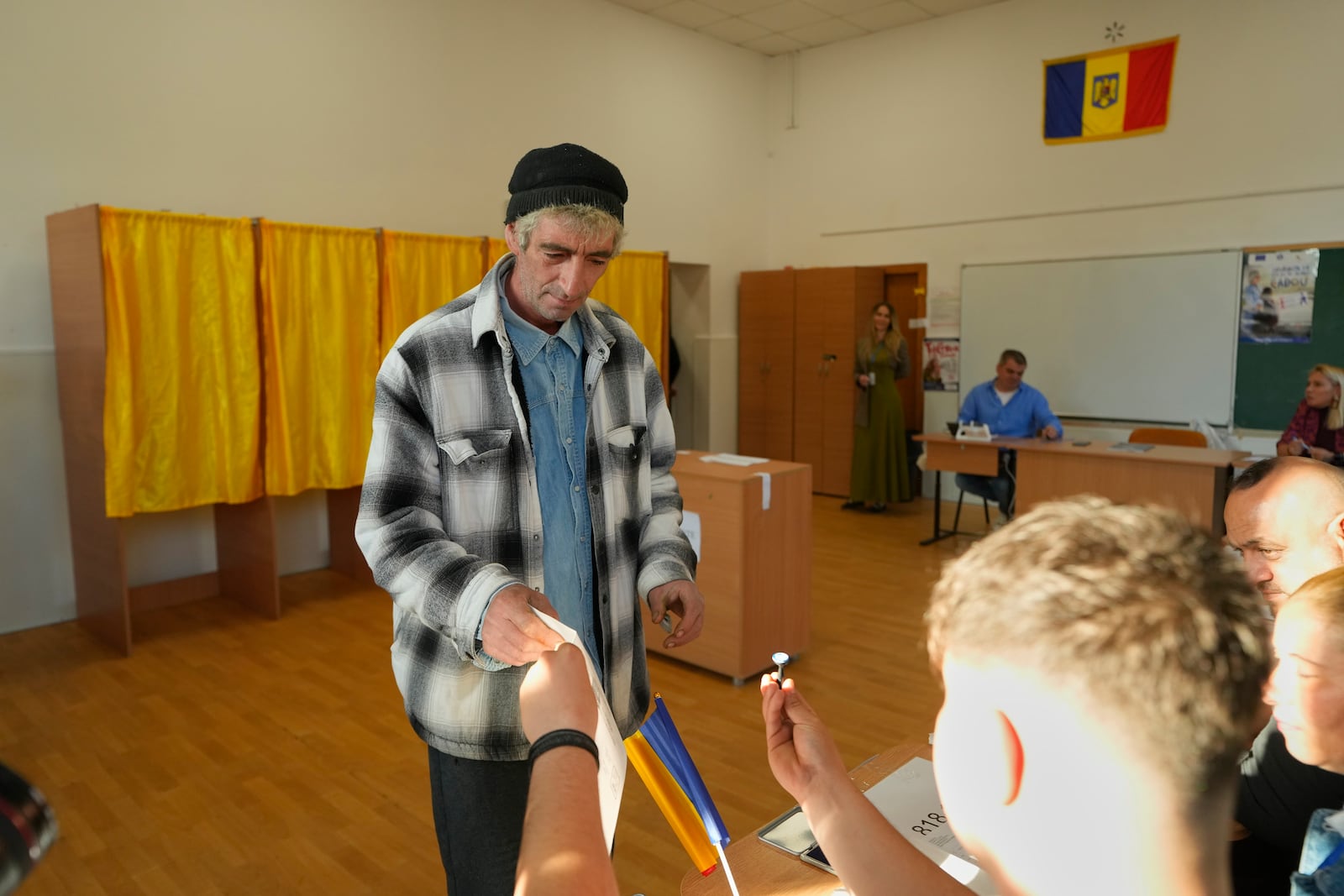 A man receives a voting stamp before casting his vote in the first round of the presidential election redo in Bucharest, Romania, Sunday, May 4, 2025. (AP Photo/Vadim Ghirda)