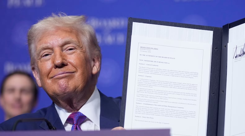President Donald Trump holds up a signed resolution during a Board of Peace meeting at the U.S. Institute of Peace, Thursday, Feb. 19, 2026, in Washington. (AP Photo/Mark Schiefelbein)
