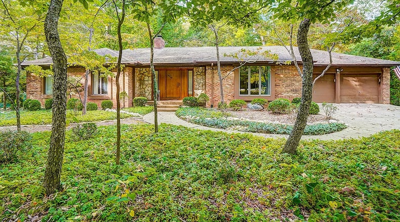 The front of the home features mature trees, an attached two-car garage with oversized concrete driveway, a circular path and a front entry surrounded by stone. Contributed photos