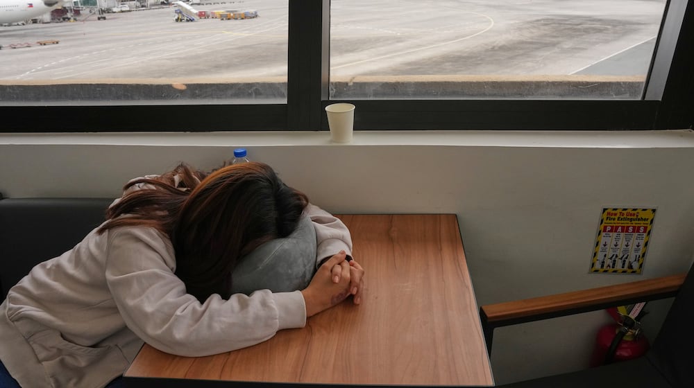 An overseas Filipino worker sleeps as she waits for updates on her cancelled flight to the Middle East at Manila's International Airport, Philippines on Monday, March 2, 2026. (AP Photo/Aaron Favila)
