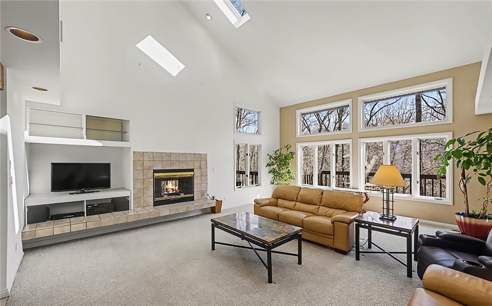 The living room has a vaulted ceiling, carpeting, skylights and a double sided woodburning fireplace with raised tile hearth and built in entertainment center. CONTRIBUTED