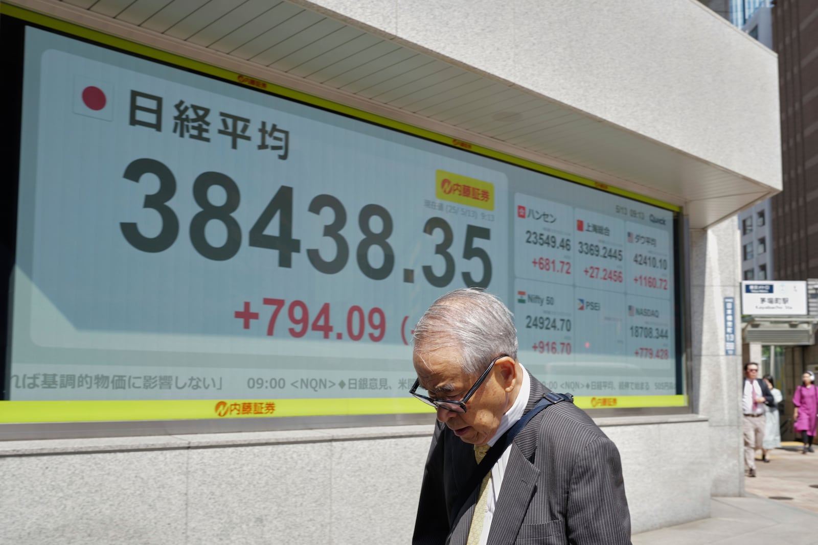 A person walks in front of an electronic stock board showing Japan's Nikkei index at a securities firm Tuesday, May 13, 2025, in Tokyo. (AP Photo/Eugene Hoshiko)