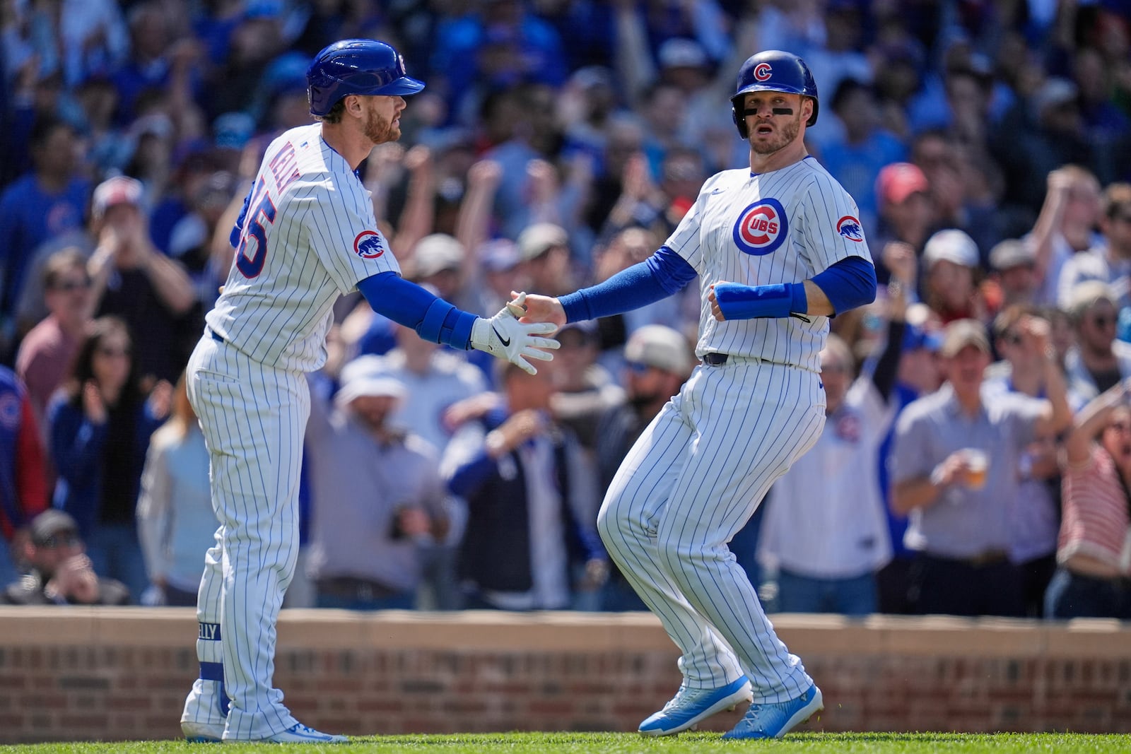 Chicago Cubs' Happ, right, slaps hands with Carson Kelly (15) after scoring on a double by designated hitter Seiya Suzuki (27) during the eighth inning of a baseball game against the Cincinnati Reds, Saturday, May 31, 2025, in Chicago. (AP Photo/Erin Hooley)