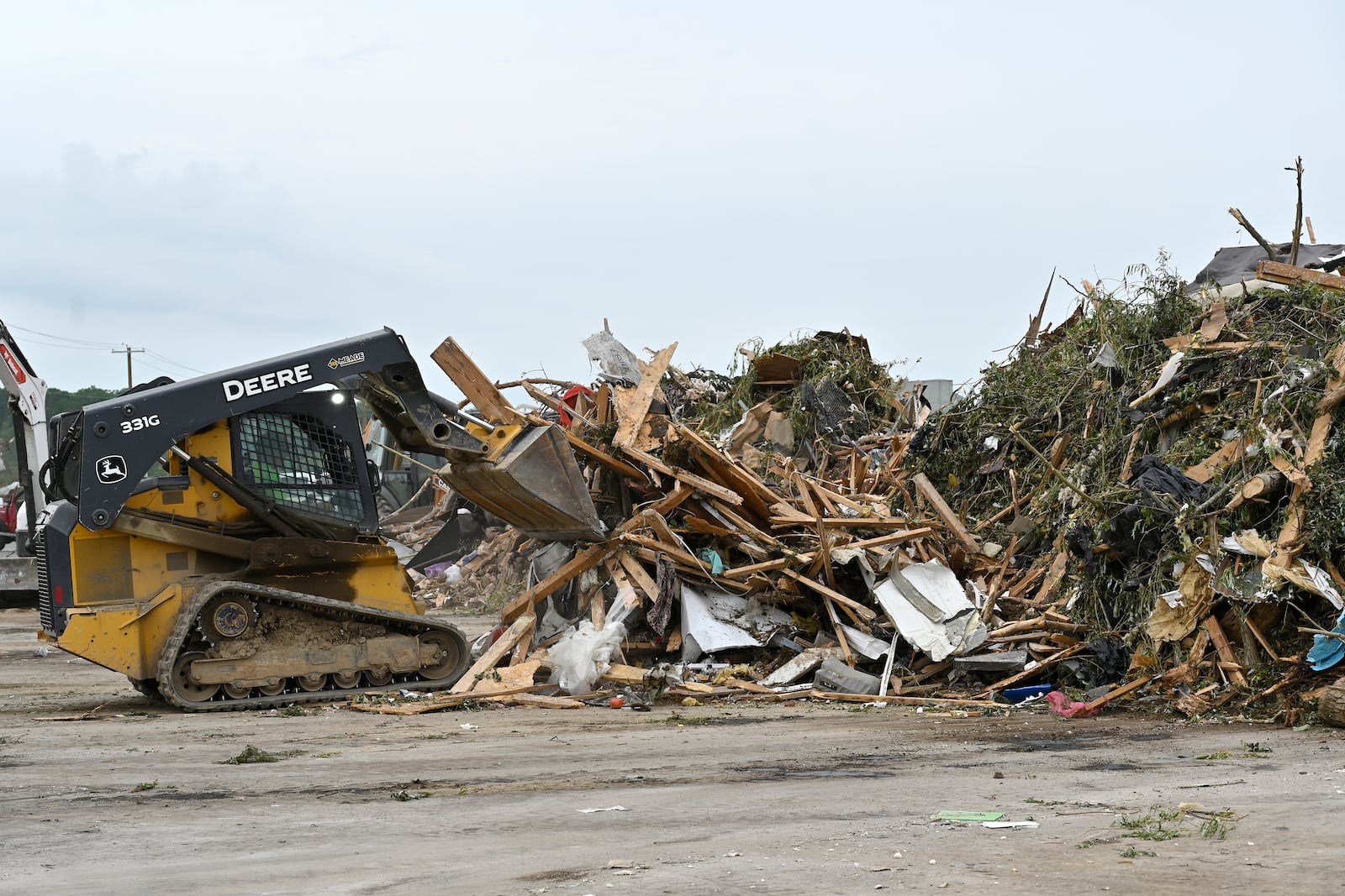 Workers pile debris from storm damage into piles for disposal at the London-Corbin Airport in London, Ky., Monday, May 19, 2025. (AP Photo/Timothy D. Easley)