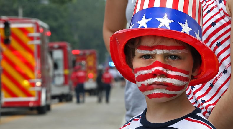 Corbin Buehler shows his patriotic spirit as he waits patiently along Enon-Xenia Road for more candy to be thrown his way during the annual Enon Fourth of July Parade Thursday.