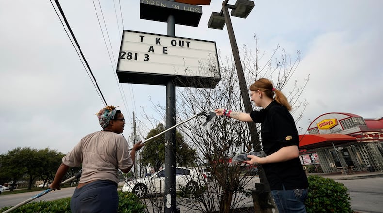 FILE - Ieisha Dede, left, and Cali Malatek put up a takeout sign outside a Denny's restaurant, March 17, 2020, in Spring, Texas. (AP Photo/David J. Phillip, File)