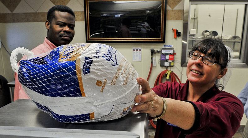 Barnaby Ofori, from the Department of Weights and Measures, watches as Rose Ray, assistant head meat cutter at Kroger in Urbana, weighs a turkey on the meat department scale Tuesday. Staff photo by Bill Lackey