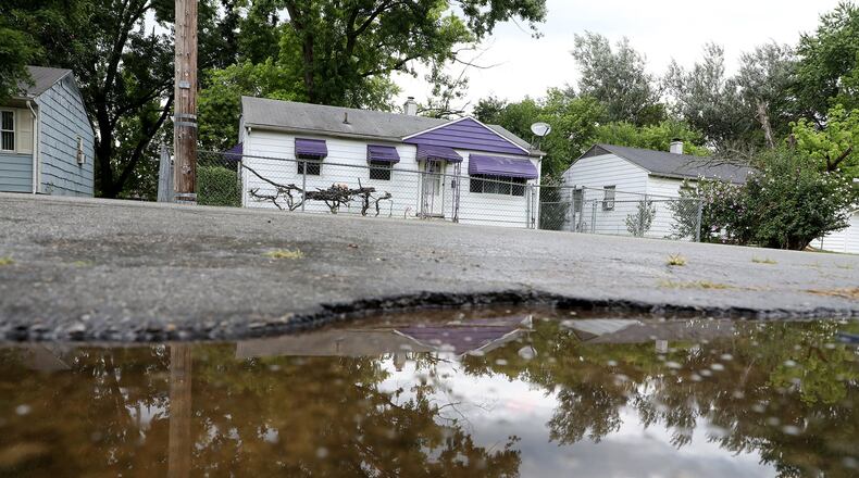A rain puddle reflects the neighborhood along Russell Avenue where Gary Cameron, 21 of Springfield was shot and killed early Friday morning. Bill Lackey/Staff
