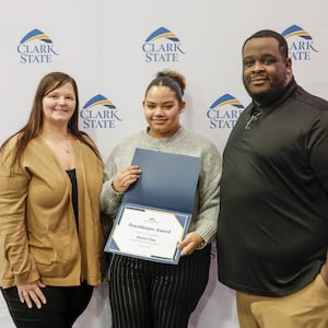 Sierra Clay, center, of Global Impact STEM Academy, next to her mother Jennifer Clay-McCockran, left, and stepfather Demetrius McCockran as she shows the Peacekeeper Award she received at Clark State College's annual MLK luncheon and awards ceremony at the Hollenbeck Bayley Center on Friday, Jan. 16, 2026, in Springfield. JOSEPH COOKE/STAFF