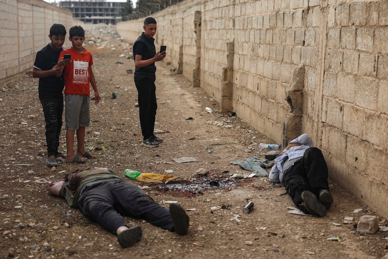 EDS NOTE: GRAPHIC CONTENT - Syrian boys take pictures with their mobile phones of the bodies of Shanaya's town mayor Houssam Warawar and his son Haidar, who were killed in the town of Sahnaya, south of Damascus, Syria, Thursday, May 1, 2025, a day after clashes erupted between members of the minority Druze sect and pro-government fighters. (AP Photo/Ghaith Alsayed)