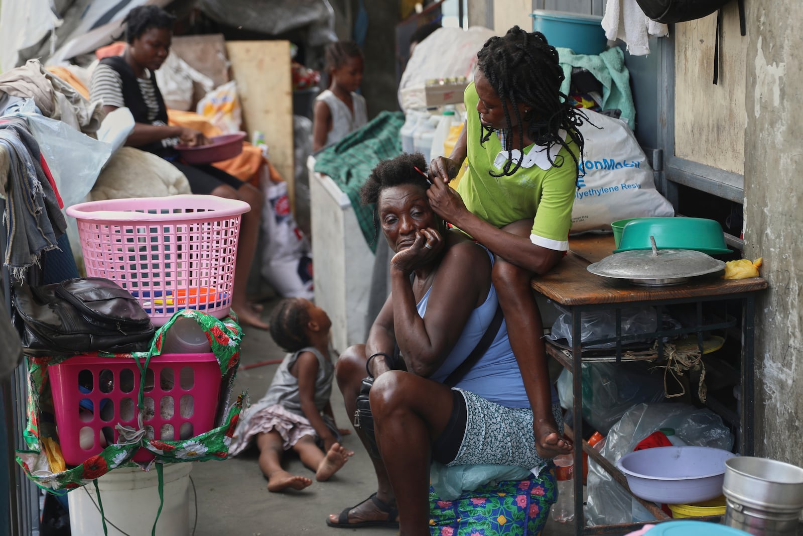 A woman combs the hair of another at a shelter for families displaced by gang violence, in Port-au-Prince, Haiti, Thursday, May 22, 2025.(AP Photo/Odelyn Joseph)