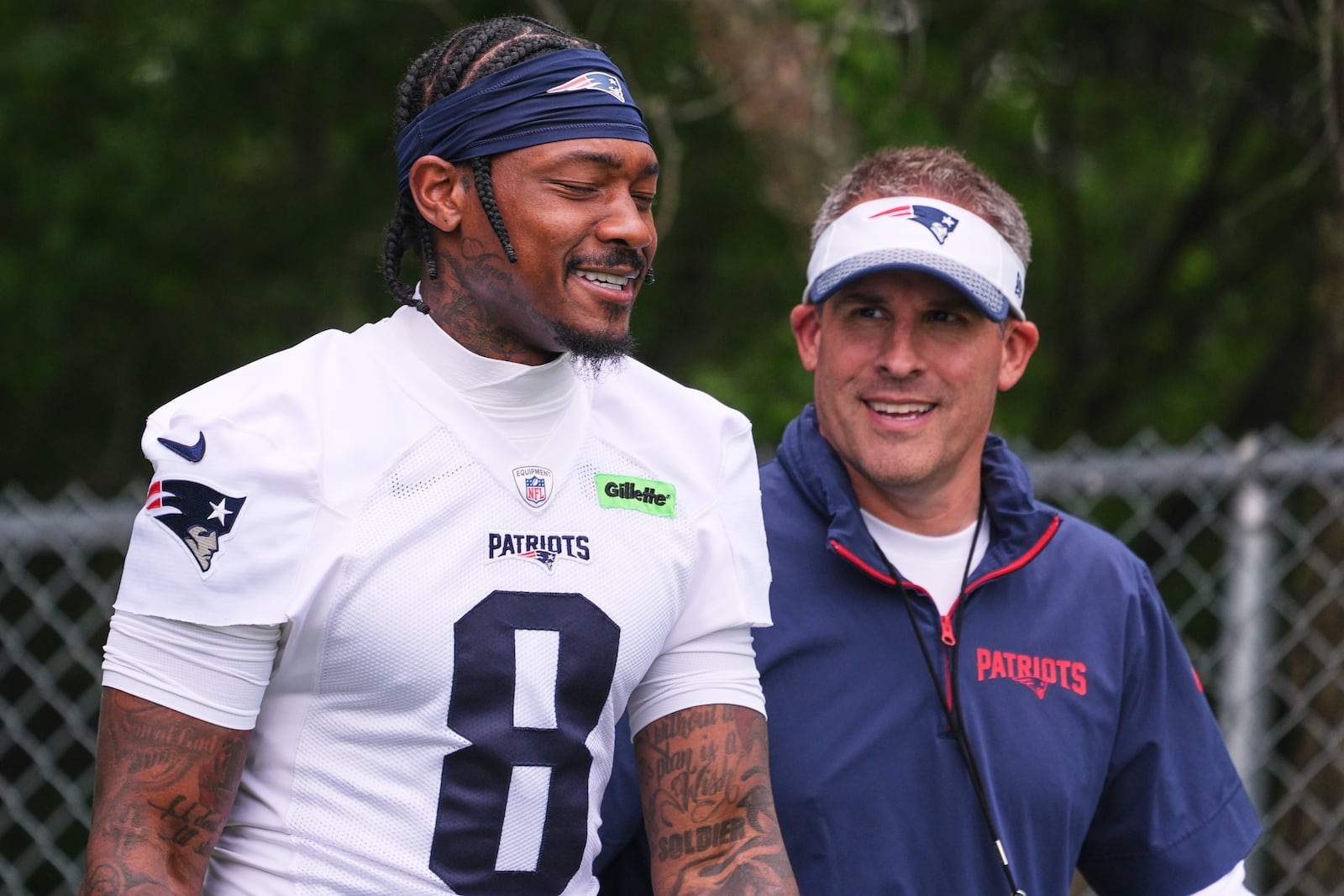 New England Patriots wide receiver Stefon Diggs, left, smiles while walking with offensive coordinator Josh McDaniels during an NFL football practice, Monday, June 9, 2025, in Foxborough, Mass. (AP Photo/Charles Krupa)