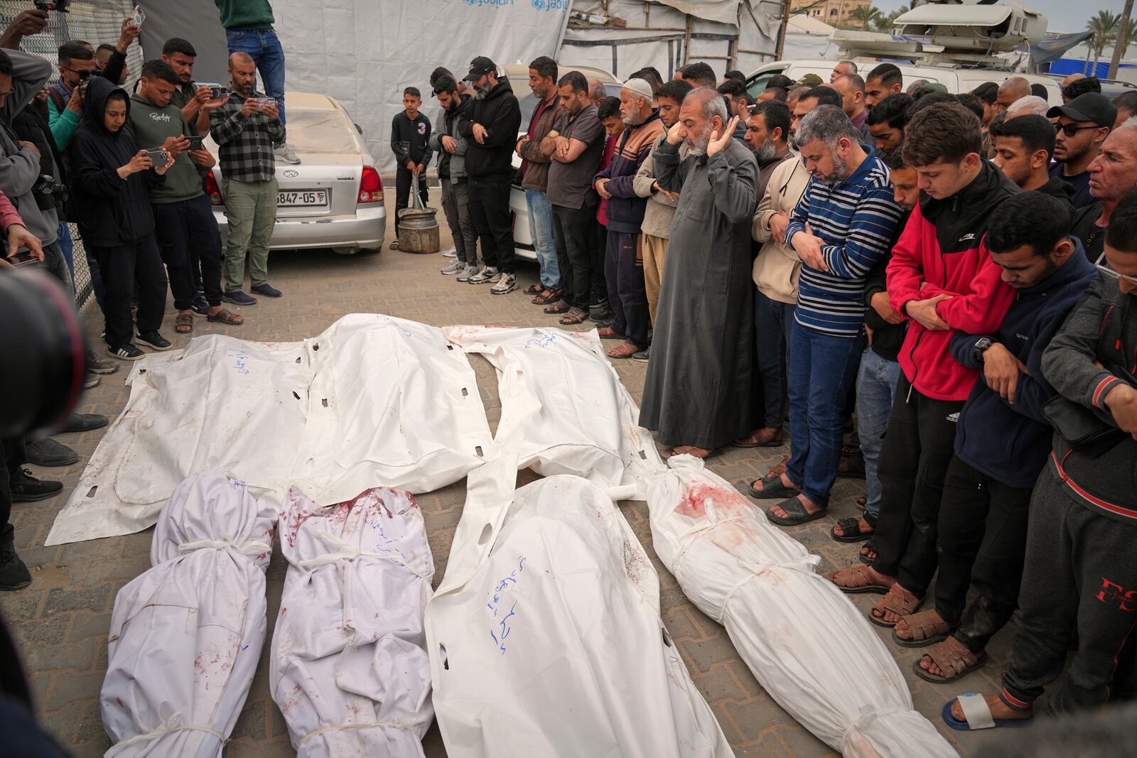 Palestinians pray over the bodie of Abdullah Habbash, along with the bodies of six brothers from the Abu Mahadi family, all members of a Palestinian charity organization linked to Hamas, who were killed earlier in an Israeli army strike on the car they were traveling in, during their funeral in Deir al-Balah, central Gaza Strip, Sunday, April 13, 2025. (AP Photo/Abdel Kareem Hana)"
