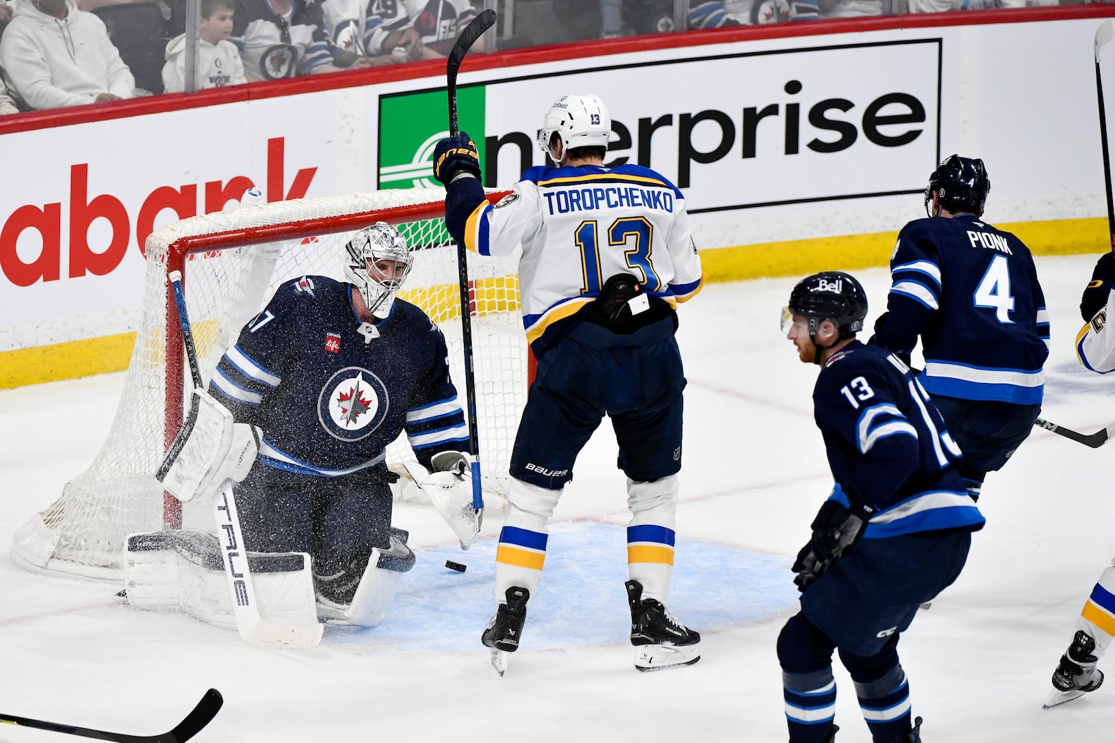 St. Louis Blues' Alexey Toropchenko (13) celebrates a goal by Radek Faksa (not shown) against Winnipeg Jets goaltender Connor Hellebuyck, left, during the second period of Game 7 in an NHL hockey first-round playoff series in Winnipeg, Manitoba, Sunday, May 4, 2025. (Fred Greenslade/The Canadian Press via AP)