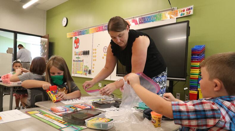 Clark and Champaign school districts have reported over 200 new COVID cases. Clark-Shawnee Local Schools, where students and teachers at Shawnee Elementary School sorted through their supplies on the first day of classes, has extended their masking requirement through Oct. 1. BILL LACKEY/STAFF