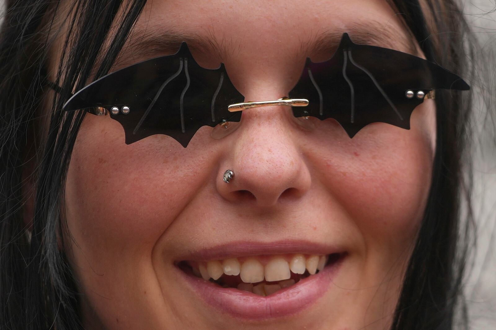 A music fan wears a sunglasses depicting bats to commemorate the death of Ozzy Osbourne at the Black Sabbath Bridge in Birmingham, Wednesday, July 23, 2025. (AP Photo/Kin Cheung)