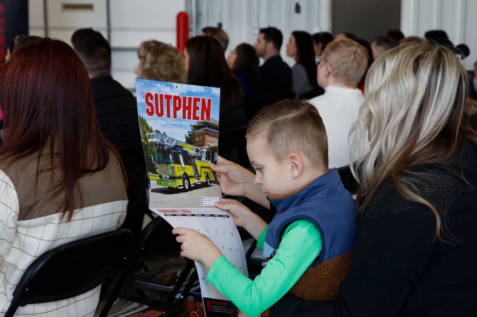 Bryan Laney, son of Sutphen general manager BJ Laney, looks over a Sutphen calendar during a grand opening ceremony for Sutphen new 185,00 square foot manufacturing plant in Urbana. BILL LACKEY/STAFF