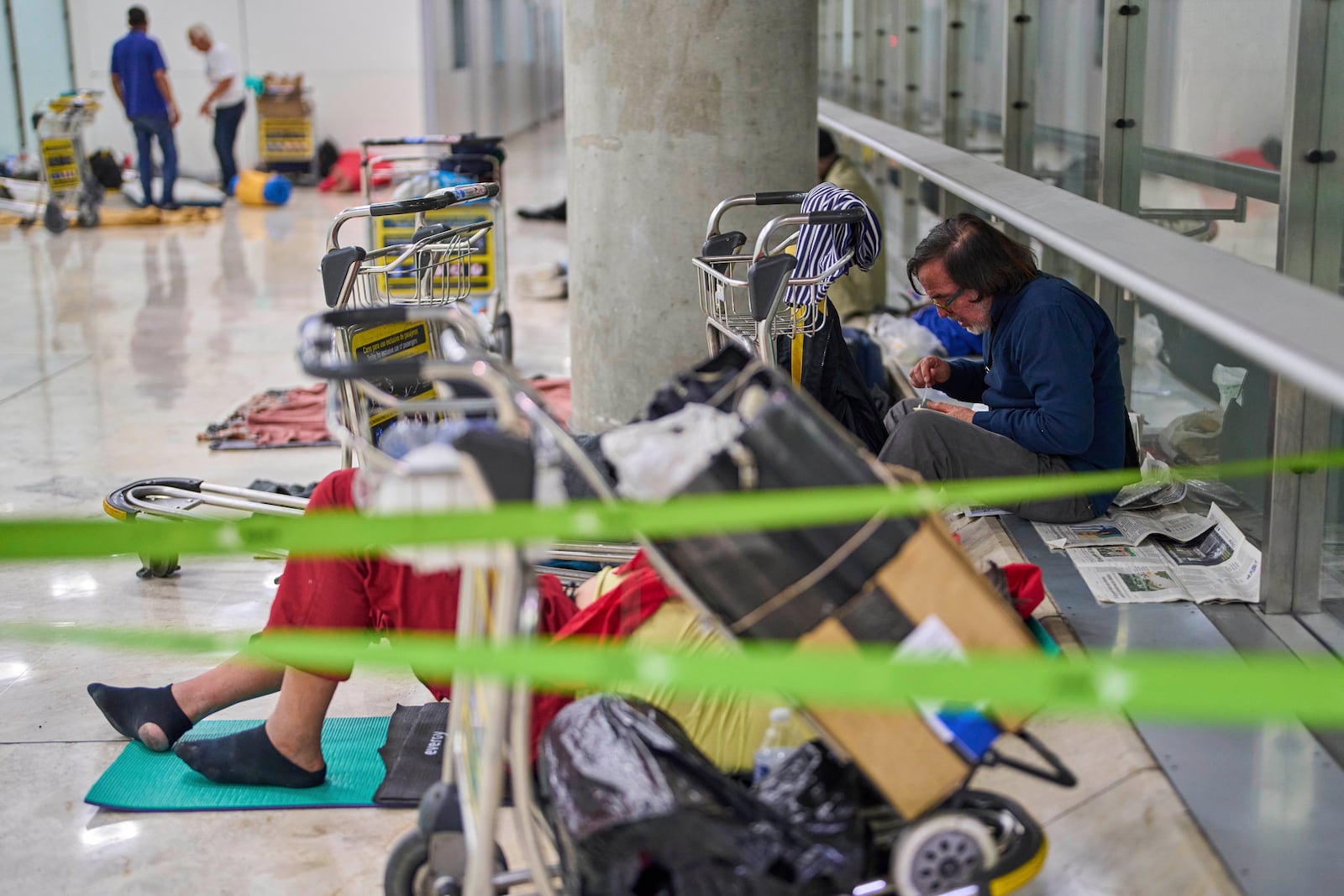 A person eats sitting on the floor of Terminal 4 at Adolfo Suarez-Madrid Barajas Airport in Madrid, Spain, Thursday, May 15, 2025. (AP Photo/Manu Fernandez)