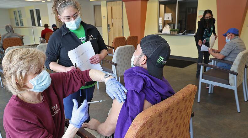 Dianne Stimpson, a nurse at The Rocking Horse Center, gives a Spanish-speaking man the COVID vaccine as an interpreter explains what's happening Friday during the Center's open vaccine clinic. Clark County's health commissioner is encouraging residents to get vaccinated as the county is ranked the highest in the state for COVID-19 case spread. BILL LACKEY/STAFF