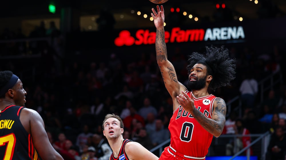 Chicago Bulls guard Coby White (0) shoots over Atlanta Hawks forward Onyeka Okongwu, left, during the first half of an NBA basketball game, Sunday, Dec. 21, 2025, in Atlanta. (AP Photo/Colin Hubbard)