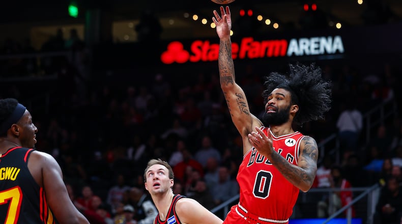Chicago Bulls guard Coby White (0) shoots over Atlanta Hawks forward Onyeka Okongwu, left, during the first half of an NBA basketball game, Sunday, Dec. 21, 2025, in Atlanta. (AP Photo/Colin Hubbard)