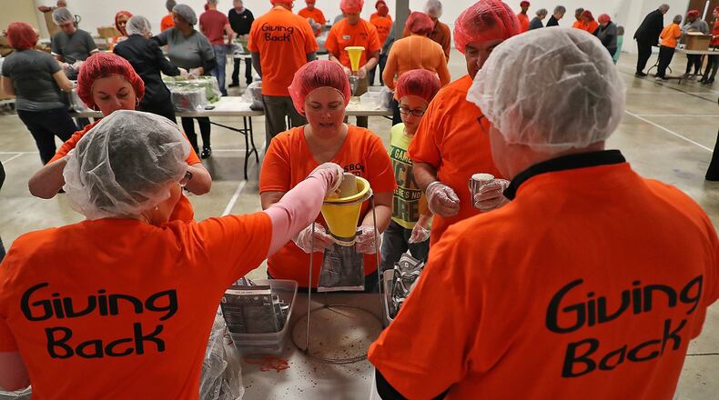 Employees from Coldwell Banker Realty and community members join forces with The Pack Shack to make 28,000 meals bags Wednesday evening at the Fellowship Christian Church. BILL LACKEY/STAFF