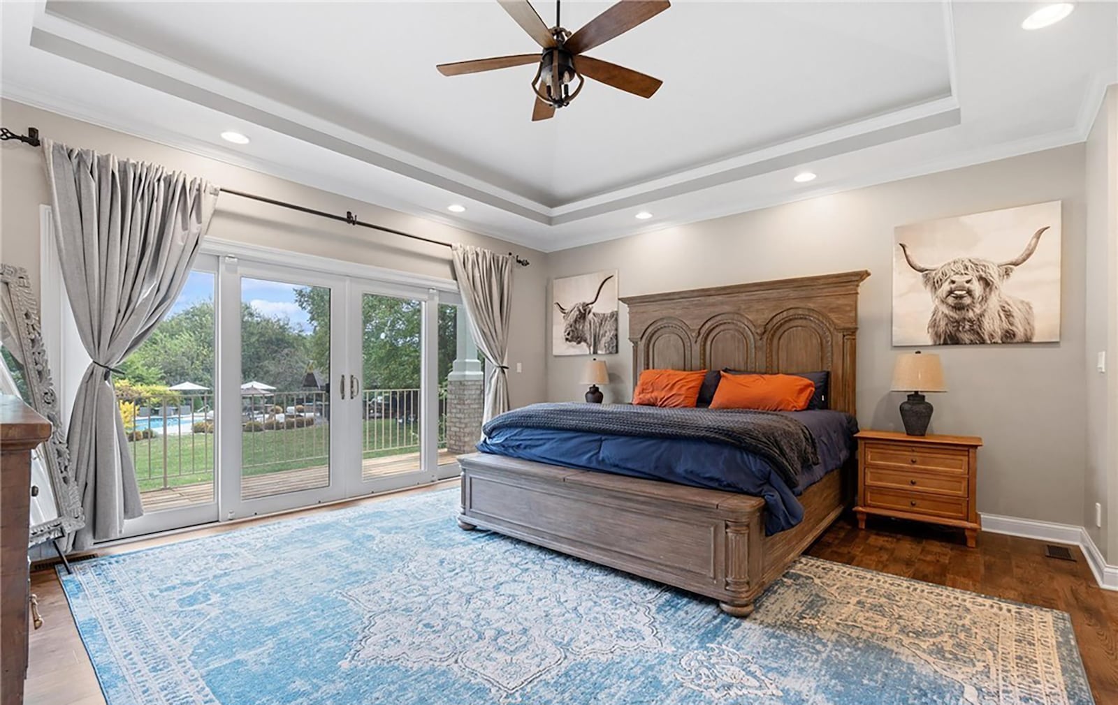 The first floor primary bedroom suite has hardwood flooring, a tray ceiling and French doors opening to the rear deck. CONTRIBUTED