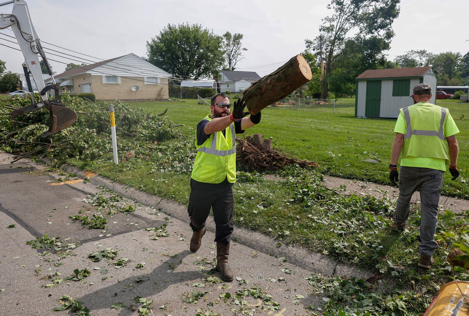 Quienten Sparks, of the Clark County Engineer Road Department, tosses a tree branch in a truck to clean up debris on Monday, July 21, 2025, following a storm that happened over the weekend in Moorefield Township. JOSEPH COOKE/STAFF