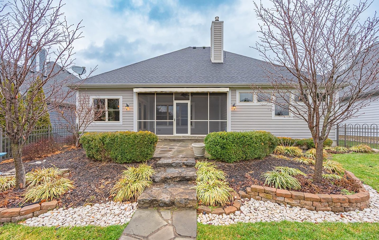 The back of the home features a screened in patio, flagstone patio with a walkway to the backyard. The yard is surrounded by a metal fence. CONTRIBUTED