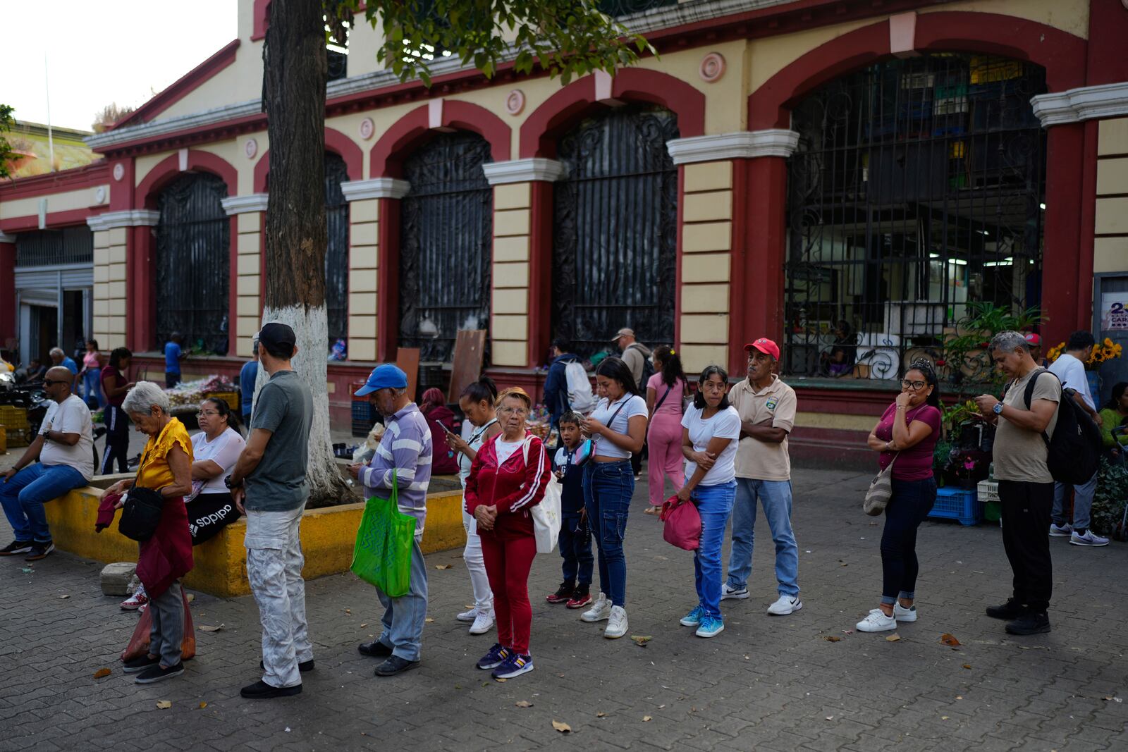 People wait for a bank to open in Caracas, Venezuela, Friday, April 11, 2025. (AP Photo/Ariana Cubillos)