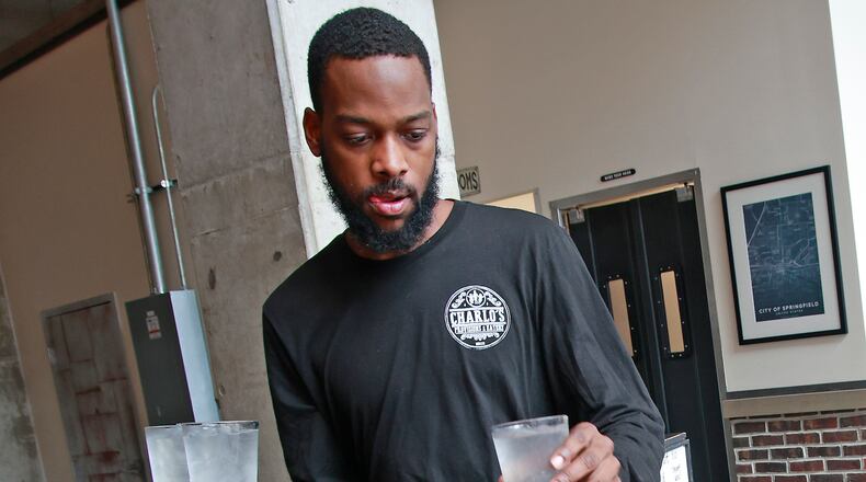 Demetrius Jones, a waiter at Charlo's Provisions & Eatery in downtown Springfield, delivers drinks to a table Wednesday, August 7, 2024. BILL LACKEY/STAFF