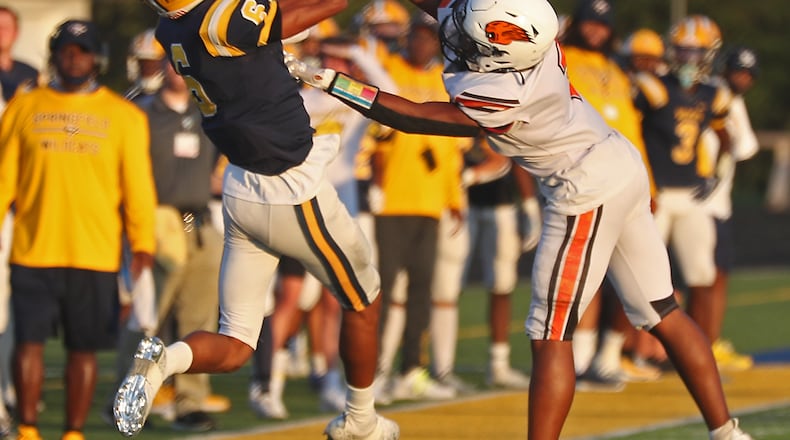 Shawn Thigpen catches a pass under pressure from Beavercreek's Devin Garnes in the first quarter of Friday night's game in Springfield. BILL LACKEY/STAFF