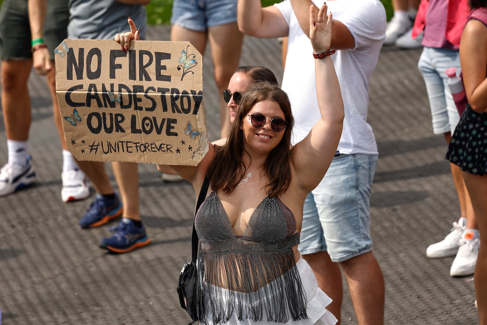 A woman holds a placard as Odymel B2B and Pegassi perform at the Tomorrowland music festival in Boom, Belgium, Friday, July 18, 2025, two days after a huge fire on Wednesday severely damaged the main stage. (AP Photo/Omar Havana)