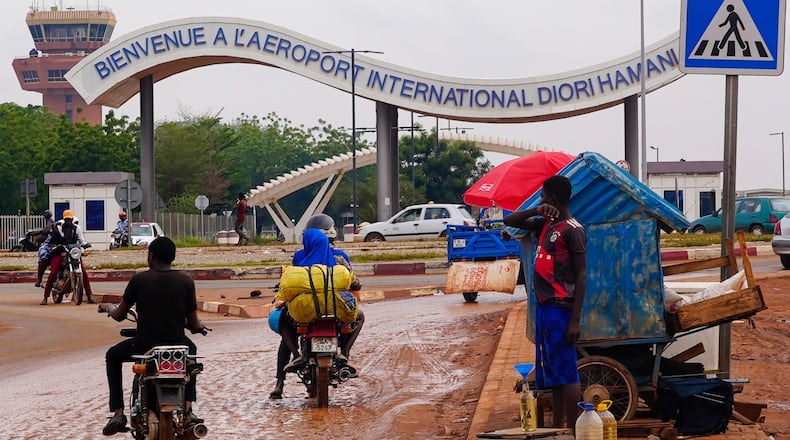 FILE- Motorcyclists ride by the entrance of the airport in Niamey, Niger, Tuesday, Aug. 8, 2023. (AP Photo/Sam Mednick, File)