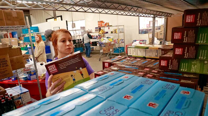 Maggie Yontz stocks the shelves of the food pantry with cereal Monday, Dec. 5, 2022 at the Second Harvest Food Bank. BILL LACKEY/STAFF