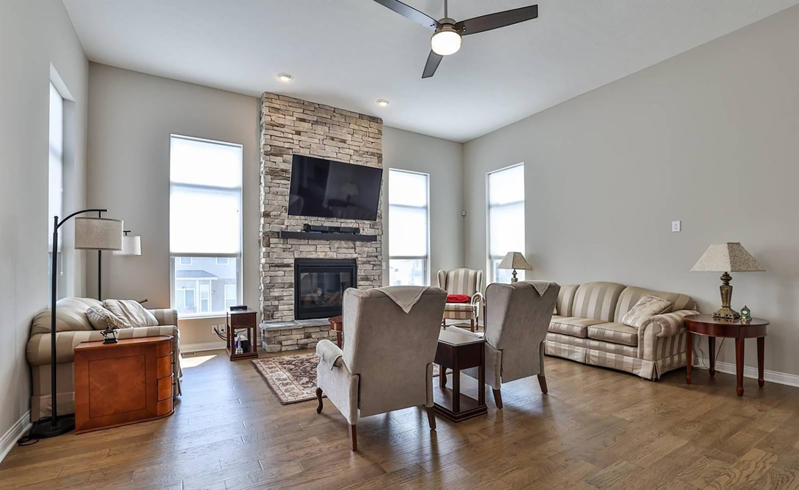 The great room has a gas stone fireplace with raised hearth, a ceiling fan and recessed lighting.