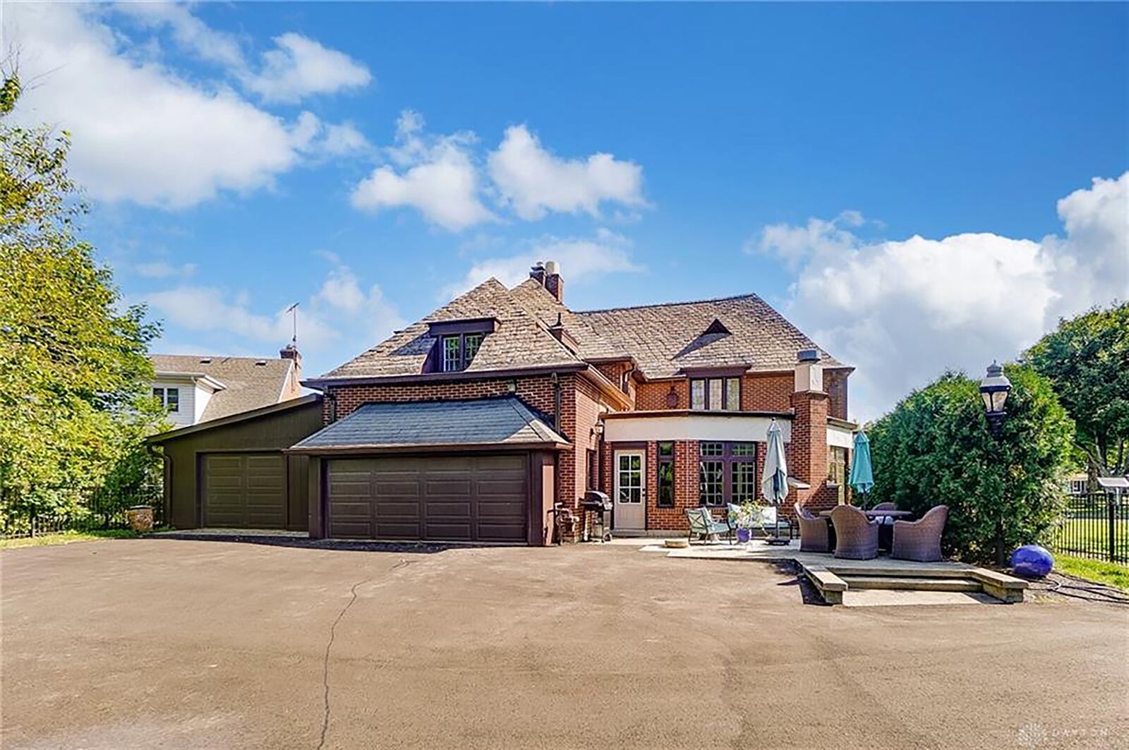 The home has a three car side entry attached garage, asphalt driveway connected to the rear patio and a metal fence around the rear yard.