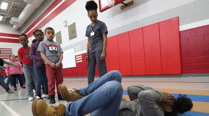 McKenzie Rucker, a senior at the Springfield-Clark County CTC, watches as students at Springfield’s Lincoln Elementary practice stopping, dropping and rolling Thursday during a fire safety program. The program was put together by McKenzie, Ashlyn Sergent and Caleb Wirth as their senior project at the CTC. Bill Lackey/Staff