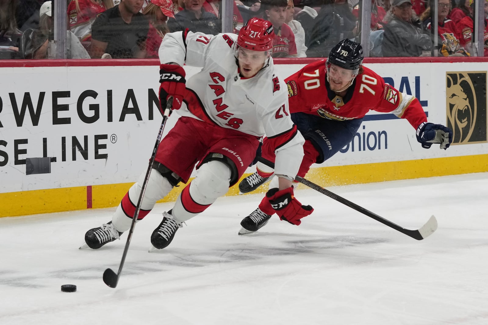 Carolina Hurricanes defenseman Alexander Nikishin (21) and Florida Panthers center Jesper Boqvist (70) go after the puck during the second period in Game 4 of the NHL hockey Stanley Cup Eastern Conference finals, Monday, May 26, 2025, in Sunrise, Fla. (AP Photo/Lynne Sladky)