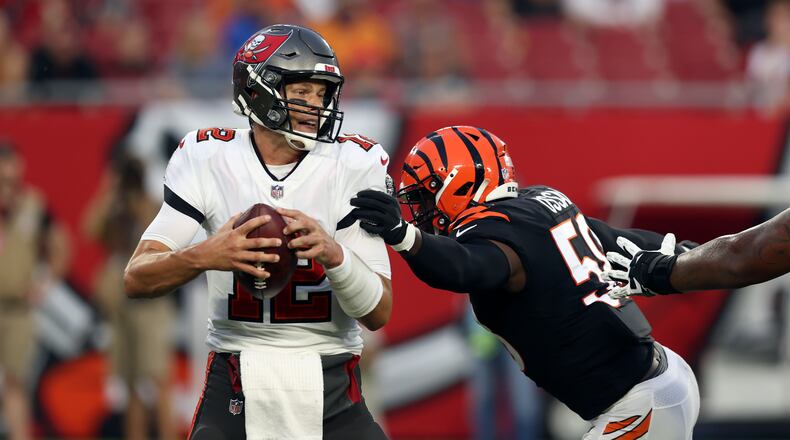 Tampa Bay Buccaneers quarterback Tom Brady (12) eludes Cincinnati Bengals defensive end Joseph Ossai (58) during the first half of an NFL preseason football game Saturday, Aug. 14, 2021, in Tampa, Fla. (AP Photo/Mark LoMoglio)