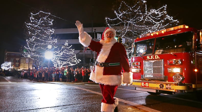 Santa waves to the crowd as he arrives in a Springfield Fire Truck Saturday during the Holiday in the City festival. BILL LACKEY/STAFF