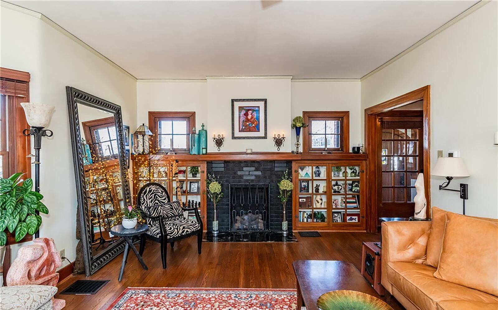 The living room has original hardwood flooring and a fireplace with built in bookcases flanking it.