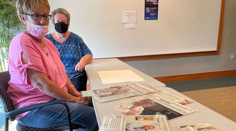 Rhonda Sagraves and Patty Davis look over newspaper clippings detailing the breast cancer diagnosis of Sagraves' husband, Greg, while sitting in the Springfield Cancer Center.