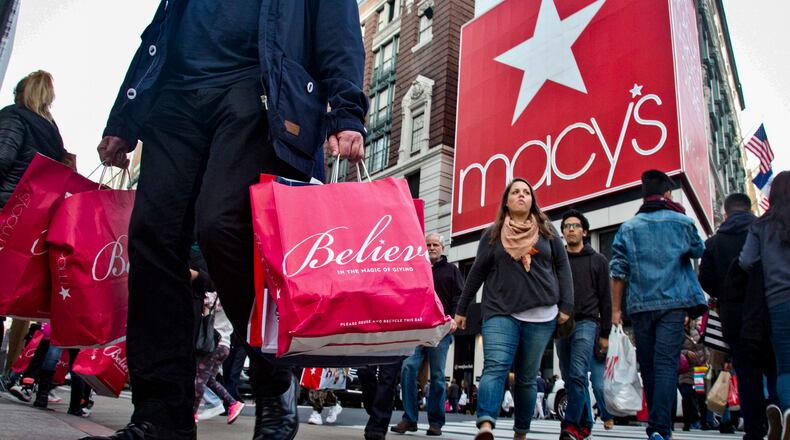 FILE - This file photo from Monday Oct. 17, 2016, shows shoppers and pedestrians in a crosswalk near a giant billboard next to Macy's flagship department store in Herald Square in New York. (AP Photo/Bebeto Matthews, File)