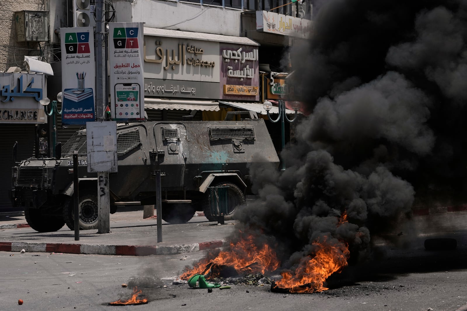 An Israeli armoured vehicle drives near burning tires during a military raid in the West Bank city of Nablus, Tuesday, June 10, 2025. (AP Photo/Majdi Mohammed)