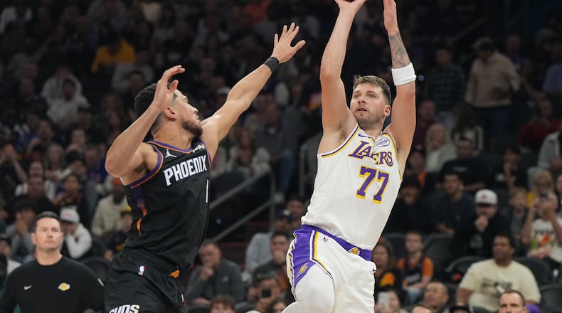 Los Angeles Lakers guard Luka Doncic (77)looks to shoot over Phoenix Suns guard Devin Booker, front left, during the first half of an NBA basketball game, Sunday, Dec. 14, 2025, in Phoenix. (AP Photo/Rick Scuteri)