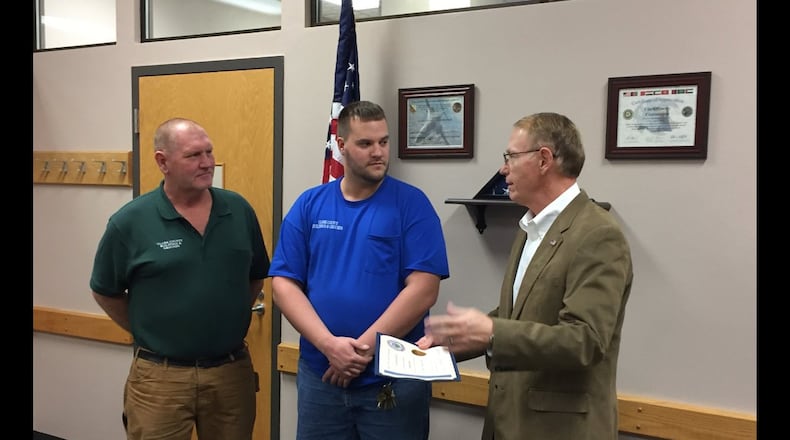 Clark County Commissioner Richard Lohnes awards Mike Yinger, in green, and Tanner Croley a proclamation.