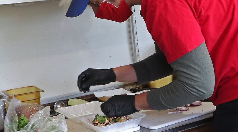 Louie Ortega, owner of the Painted Pepper food truck, prepares food for a customer while set up in the Ridgewood Neighborhood of Springfield Wednesday. BILL LACKEY/STAFF