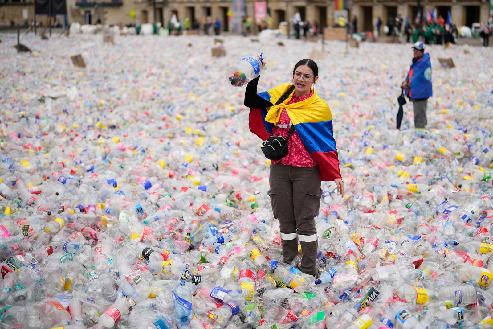 A recycler stands amid plastic bottles blanketing Plaza Bolivar in Bogota, Colombia, as part of a protest against what recyclers consider to be too low a price paid to them by companies that buy recycled materials, Tuesday, June 24, 2025. (AP Photo/Fernando Vergara)